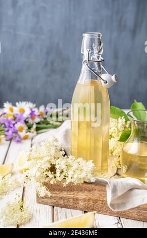 Delicious healthy refreshing beverage, sweet elderflower syrup or cordial in a glass bottle on rustic wooden background Stock Photo