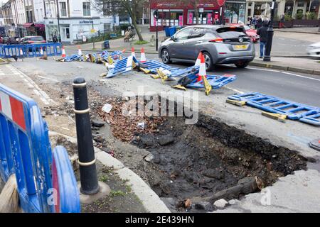 watermain burst opened up a big hole on road in blackheath village London England Stock Photo