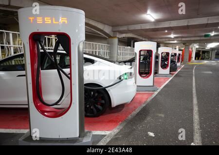 electrical car plugged into Tesla charging stations  in under cover car park, Kent, England Stock Photo