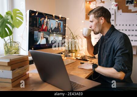 Morning coffee break during work from home. Man working on computer in office. Video conference screen remote call. Business internet telework. Stock Photo