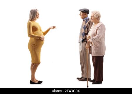 Full length profile shot of a pregnant woman talking to an elderly man and woman isolated on white background Stock Photo