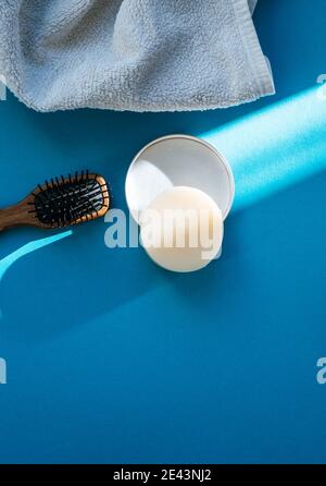 Eco-friendly haircare: Solid Shampoo Bar and a hairbrush isolated on blue coloured background Stock Photo