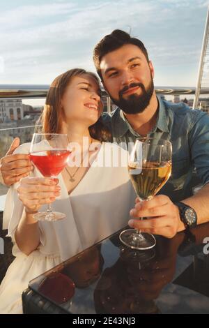 Vertical shot of a happy young couple laughing, enjoying wine on bar terrace Stock Photo
