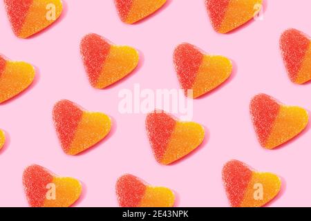 Top view flat lay composition of multicolored jelly candies in shape of heart arranged in rows on pink background Stock Photo