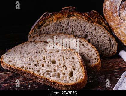 Slices of baked bread placed on wooden table in kitchen Stock Photo
