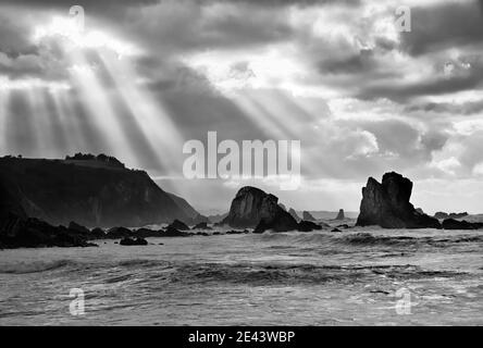 rays of light breaking through the storm clouds over the beach of Silencio in Asturias Stock Photo