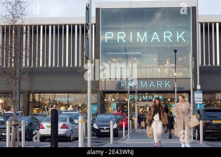 Primark shoppers with bags of shopping walk pass the parked cars, London, Greater London Stock Photo