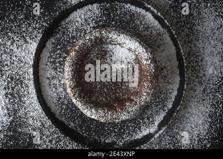 Top view of sweet chocolate coulant placed on black background with sugar powder Stock Photo