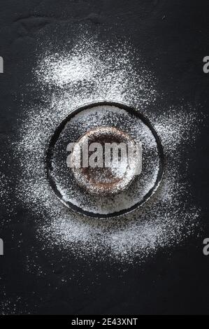 Top view of sweet chocolate coulant placed on black background with sugar powder Stock Photo