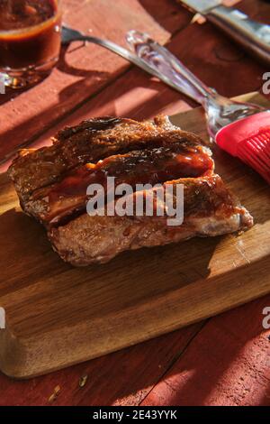 Medium rare grilled beef steak served on wooden chopping board on table in cafe Stock Photo