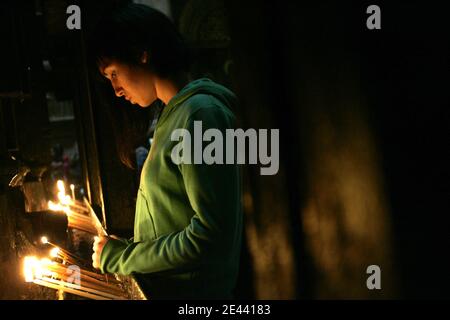 An Orthodox Christian pilgrim lights a candles next to the Edicule inside the Church of the Holy Sepulcherin Jerusalem's Old City, Israel on April 16, 2009, ahead of Orthodox Easter. Photo by Olivier Fitoussi/ABACAPRESS.COM Stock Photo