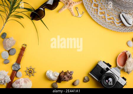 Seashells, accessories and camera on yellow background. Seaside adventures Stock Photo
