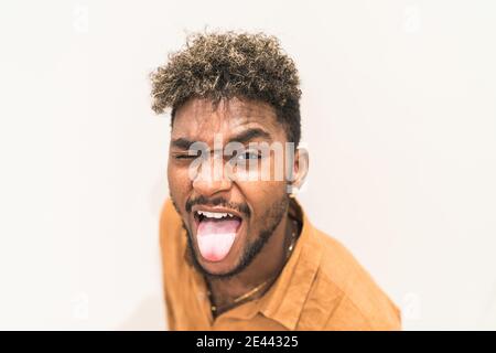 Handsome young bearded hipster black guy with curly hair and looking at camera and smiling while sitting on stairs near metal fence Stock Photo