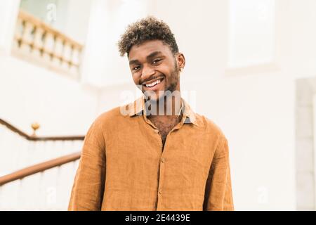 Handsome young bearded hipster black guy with curly hair dressed in casual white shirt looking at camera Stock Photo