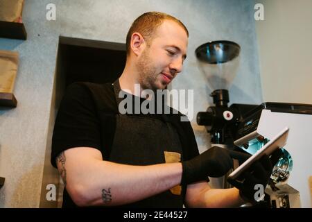 Waiter holding a tablet in hand while working in a coffee shop Stock Photo