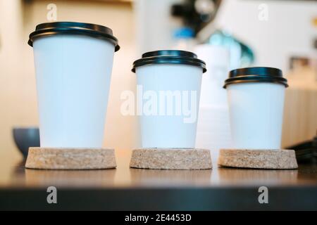 Row of assorted disposable paper cups for takeaway coffee placed on counter in coffee shop Stock Photo