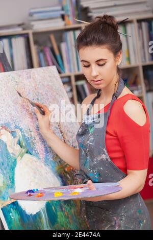 Vertical shot of a beautiful young woman painting at the workshop Stock Photo