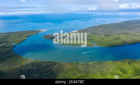 Picturesque drone view of heart shaped island covered with lush green vegetation washing by river water against sunset sky in countryside in Australia Stock Photo