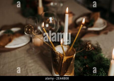 Composition with flaming candles placed in golden candleholder on table decorated for Xmas holiday Stock Photo