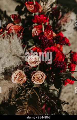 Dry palm leaves and various flowers arranged in bouquet and placed in garden as decoration for wedding party Stock Photo