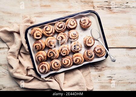 Top view of many glazed cinnamon rolls placed in rows on baking tray on wooden table Stock Photo