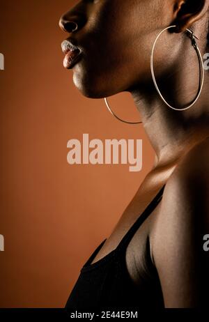 Side view of cropped unrecognizable black Woman with short hair standing against brown background Stock Photo