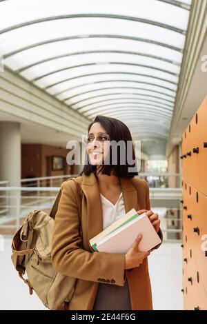 Smiling female student in smart casual outfit standing in university hallway Stock Photo