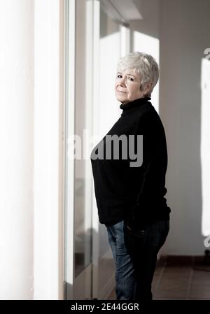 Relaxed senior Woman at home by the window on a sunny day Stock Photo