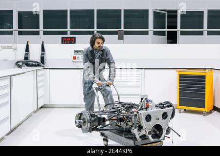 Male technician transporting disassembled motorbike on trolley while working in modern repair service workshop Stock Photo