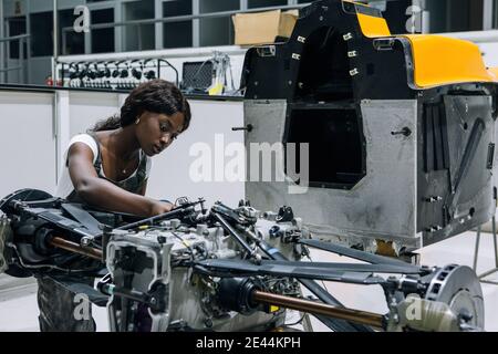 Serious young African American female mechanic assembling custom vehicle in modern repair service center Stock Photo