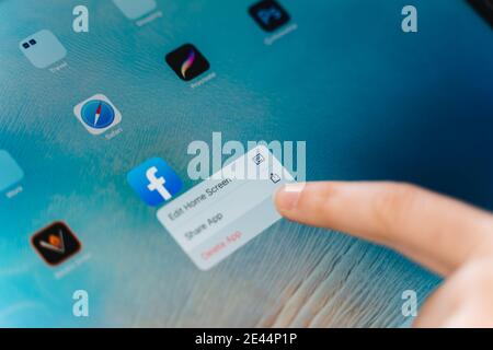 Poltava, Ukraine - jan 2021 Person deleting facebook app from phone. social media addiction. Cyberbullying online. Private data security problem Stock Photo