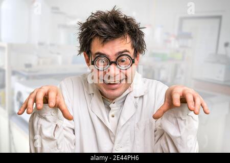 Funny and crazy scientist with glasses and white coat in laboratory Stock Photo