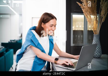 Woman on remote work or online education, using laptop computer, making notes, indoors at home. Online business, young professional at workplace Stock Photo