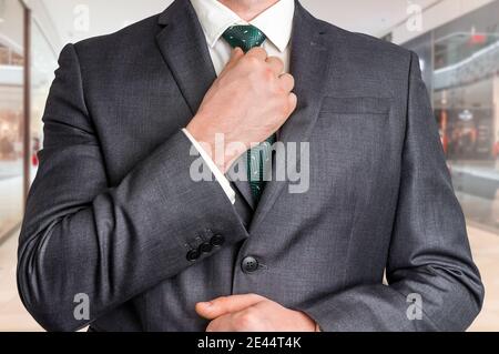 Businessman in black suit adjusting his tie in shopping center Stock Photo