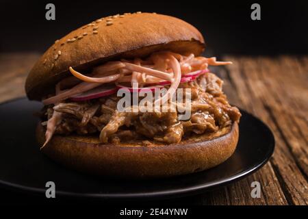 Closeup of yummy hamburger with juicy pulled pork and vegetables in toasted bun Stock Photo