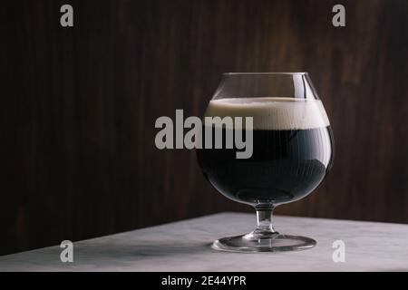 Crystal glass of dark stout beer placed marble table in bar Stock Photo