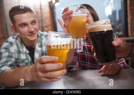 Selective focus on beer glasses in the hands of young people celebrating at beer pub Stock Photo