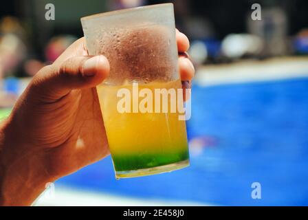 Man holding drink near the pool. Stock Photo