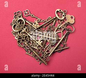 Old, vintage keys in the shape of a heart isolated on pink color bacground Stock Photo