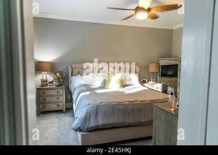 Spacious beige carpeted master bedroom with king sized bed Stock Photo