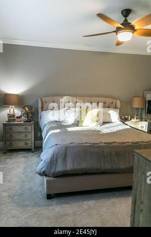 Spacious beige carpeted master bedroom with king sized bed Stock Photo