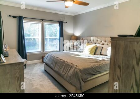 Spacious beige carpeted master bedroom with king sized bed Stock Photo