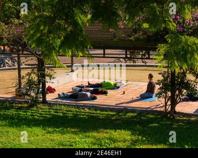 CORNELLà DE LLOBREGAT, SPAIN - Dec 29, 2018: three people doing yoga on a sunny day with their teacher in a park Stock Photo