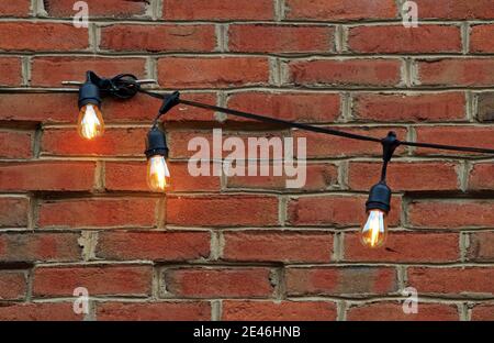 A string of lights against a red brick wall. Stock Photo