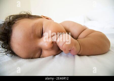 Infant falling asleep on the bed Stock Photo