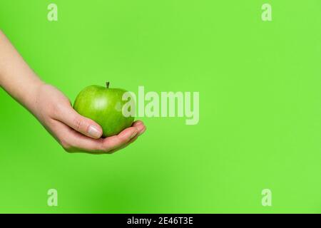 Close up on hand holding green apple in front of background - granny smith healthy eating concept with copy space Stock Photo