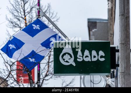 Montreal, CA - 21 January 2021:  Street sign of a SQDC marijuana store (Societe quebecoise du cannabis) in front of a quebec flag Stock Photo