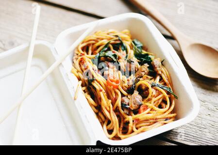 Service food order online delivery spicy spaghetti italian pasta and tomato sauce with sausage on food box, food delivery in take away boxes package o Stock Photo