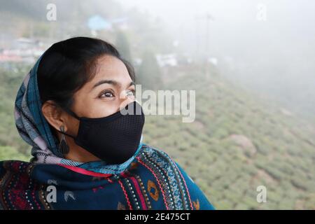 Side portrait of a mid 30s indian looking up jovially in winter wear wearing a black mask Stock Photo