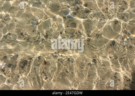 The water surface is so clear that you can see through and see the rocks below. Stock Photo